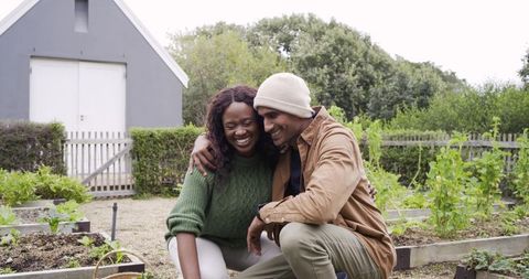 Couple tending raised garden beds and sharing joyful moment in backyard allotment near shed