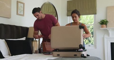 Couple packing suitcase in bedroom for travel adventure