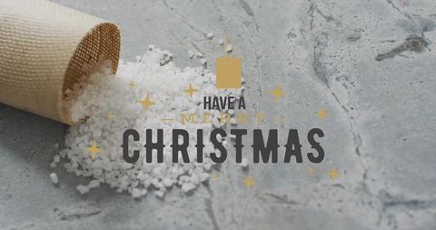Spilling coarse sea salt cone on gray stone with gold merry christmas typographic overlay