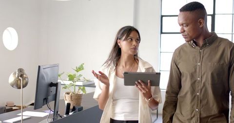 Colleagues Discussing Projects Using Tablet in Modern Office