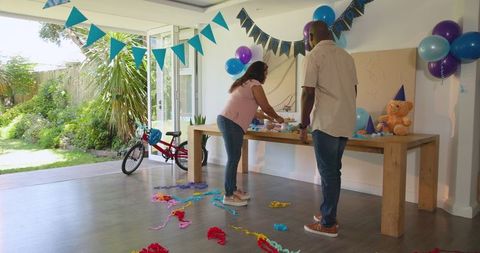 Joyful couple preparing birthday party decorations at home