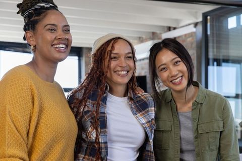 Diverse Female Coworkers Embracing in Modern Office