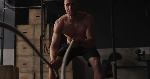 Shirtless Athletic Man Training with Battle Ropes in Gym