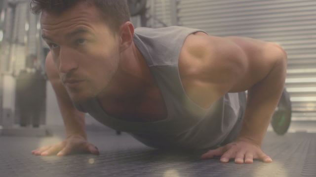 Man performing push-ups on gym floor with digital light effects radiating around him. Could be used for fitness promotions, health and wellness articles, workout-related content, or digital interface concepts.