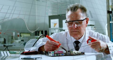 Senior technician soldering motherboard components using precision tools in electronics lab