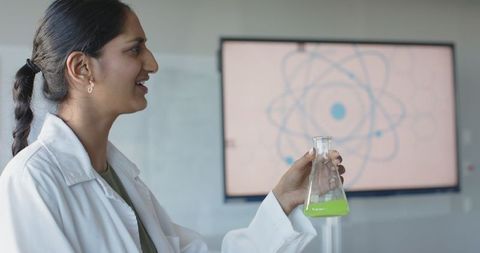 Female scientist teaching chemistry class with green liquid flask