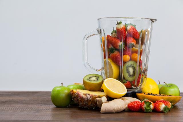 Fresh fruits and vegetables in a blender on a wooden table, ready for making a healthy smoothie. Ideal for promoting healthy eating, diet plans, nutrition, and detox recipes. Perfect for use in health blogs, diet websites, and wellness magazines.