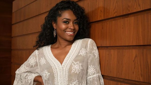 Confident woman in white lace blouse against wood wall