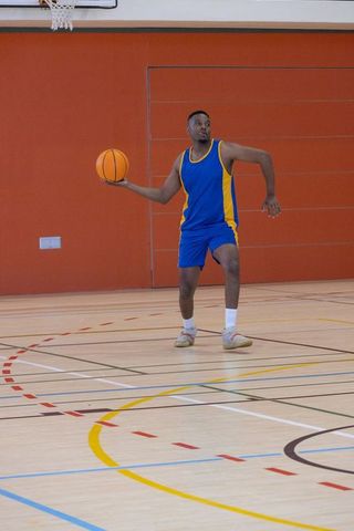 Athlete Strategizing with Basketball Indoors in Action-Packed Gym