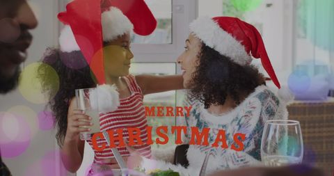 African American Mother and Daughter in Festive Santa Hats Celebrating Christmas