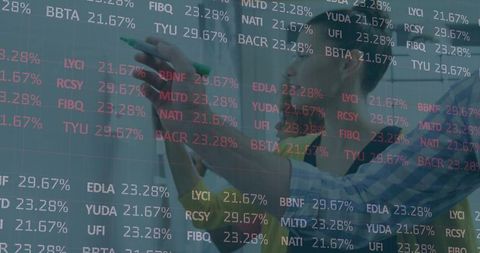 Financial analyst annotating transparent board with tickers
