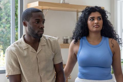 Contemplative indian woman and african american man leaning at modern kitchen counter