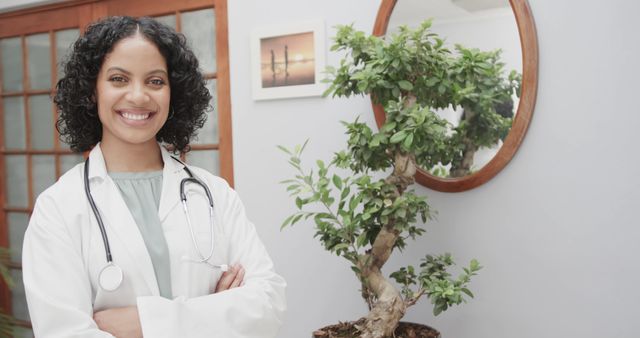 Portrait of smiling biracial female doctor standing in reception at health clinic, copy space. Medical services and healthcare, unaltered.