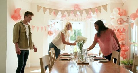 Friends preparing for celebration at home decorated with balloons