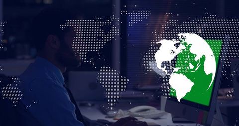 Analyst studying global data on desktop monitor with dotted world map overlay