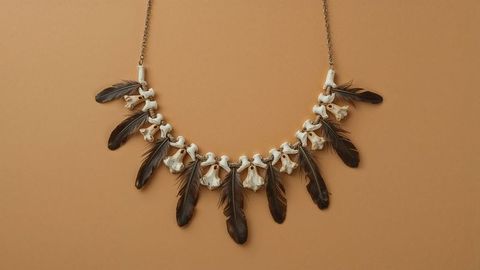 Handcrafted bone and feather necklace on tan background