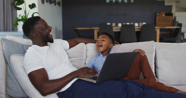 African american father and son using a laptop together. staying at home in self isolation during quarantine lockdown.