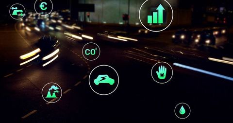 Night traffic light trails and neon green sustainability icons over urban multilane highway