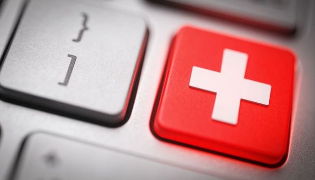Red medical cross key on keyboard representing emergency health support and telemedicine access