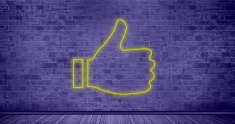 Yellow Neon Thumbs Up on Purple Brick Wall Background