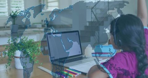 Girl raising hand during online learning at home with laptop, headphones and world map overlay