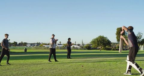 Youth cricketer batting on suburban field with teammates clapping in outdoor practice