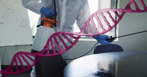 Protective worker spraying classroom disinfectant with DNA helix overlay