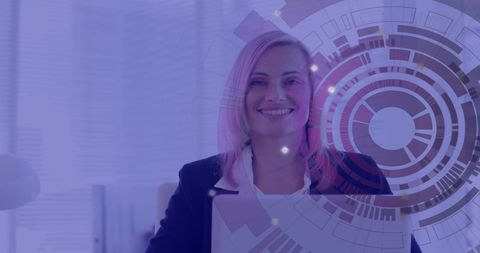 A smiling businesswoman is sitting at a desk with a laptop, overlaid by a futuristic digital data interface design. The background signifies a modern office environment. This image might be used for themes focused on business innovation, technology trends, or the modern digital workplace. Suitable for presentations, tech seminars, or articles illustrating corporate tech integration.