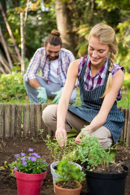 Young woman enjoying gardening in a botanical garden, planting flowers and herbs in soil. Ideal for content related to gardening, outdoor activities, hobbies, teamwork, and nature. Perfect for illustrating articles, blogs, and advertisements promoting gardening, outdoor lifestyle, and environmental awareness.