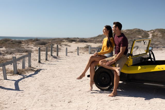 Happy caucasian couple sitting on beach buggy at sunny beach embracing and admiring the view. beach stop off on romantic summer holiday road trip.