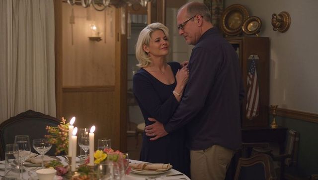 Mature couple embracing by candlelit dinner table creating romantic intimate evening