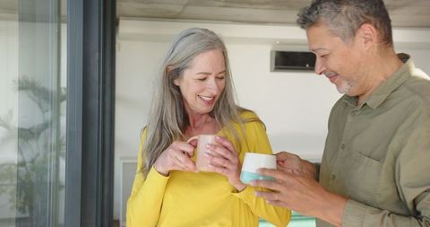 Senior Couple Enjoying Coffee Together at Home by Glass Doors