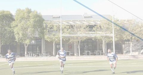 Three rugby players sprinting across artificial turf carrying ball in sunny match