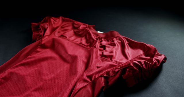 Close up of red sports tshirt lying on black floor. Sport, american football and activity.