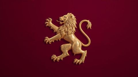 Majestic golden lion sculpture on maroon heraldic emblem