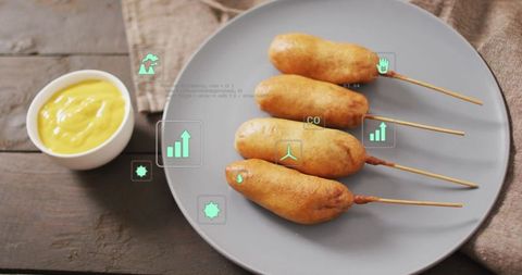 Crispy corn dogs on skewers with mustard on gray plate featuring ar food icons