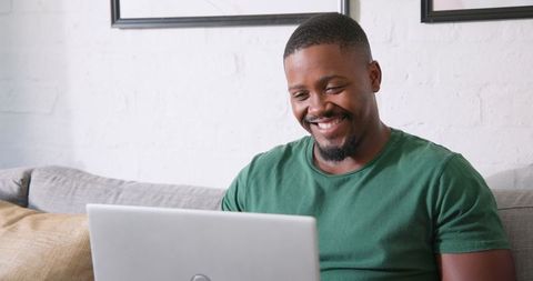 Man Smiling While Using Laptop in Casual Home Office Environment