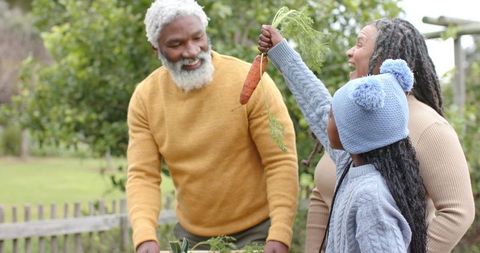Multigenerational Family Harvesting Carrot in Garden Sharing Joyful Outdoor Autumn Moment