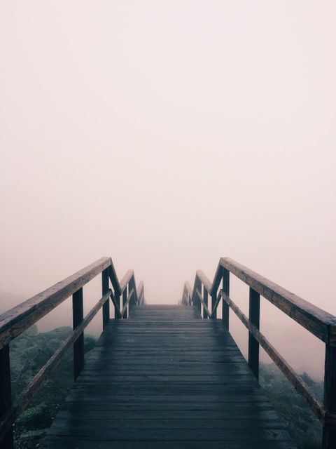 This shows a wooden walkway descending into dense fog, creating a sense of mystery and adventure. It conveys themes of exploration, tranquility, inner peace, and contemplation, making it suitable for promoting travel destinations, mindfulness content, and adventurous journeys.