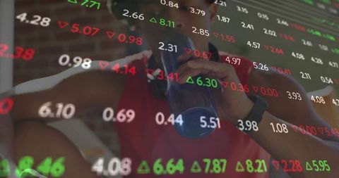 Athlete hydrating in gym with digital stock market overlay