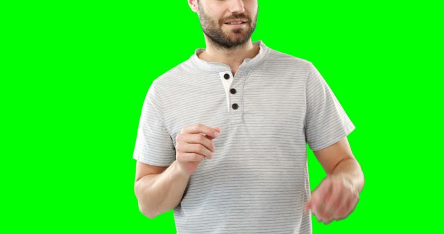 Man wearing a casual striped shirt standing against a green screen background. He is smiling and appears to be gesturing with his hands. Image can be used for advertising, promotional materials, presentations, or any project requiring an easily editable background.