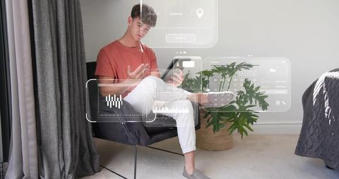 Young man interacting with tablet and futuristic transparent ui overlays in modern bedroom