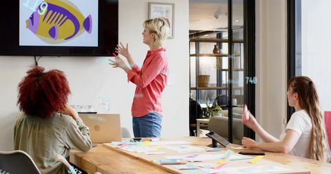 Team collaborating in modern conference room presenting colorful design concept on screen