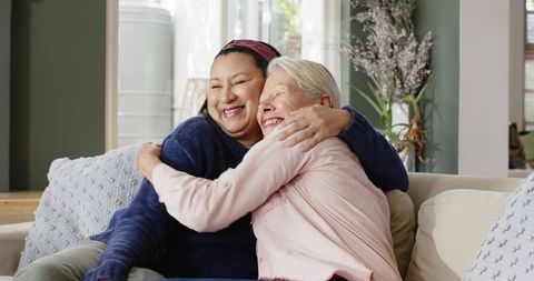 Senior Friends Embracing on Cozy Sofa in Bright Living Room