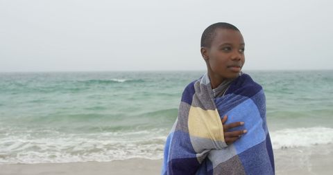 Serene African Woman Wrapped in Blanket by Ocean