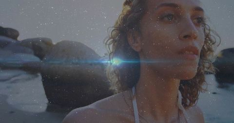 Serene hispanic woman on rocky shoreline contemplating ocean