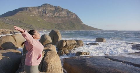 Woman Practicing Mindfulness by Ocean Waves on Rugged Cliffs