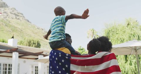 Young Man and Child Celebrating with American Flag Outdoors