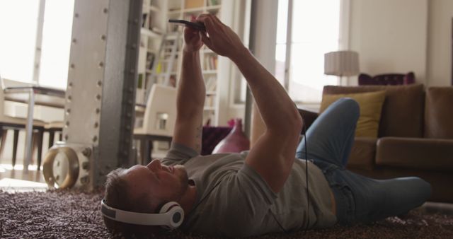 Man Relaxing on Floor Listening to Music and Using Smartphone - Download Free Stock Images Pikwizard.com