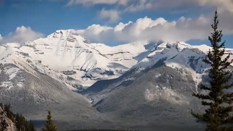 Snowcapped Mountains Under Moving Clouds in Serene Winter Landscape